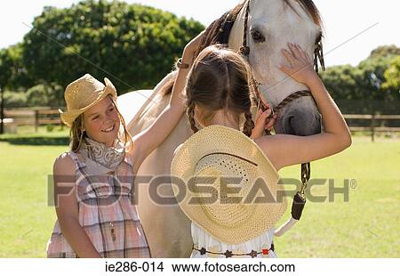 Two girls stroking a horse View Large Photo Image Picture - Two girls stroking a horse. Fotosearch