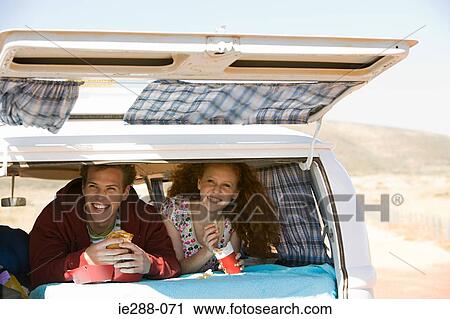 Stock Image - A couple eating fast food in a camper van. Fotosearch
