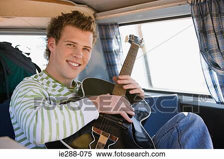 A young man playing a guitar View Large Photo Image Stock Photography - A young man playing a guitar. Fotosearch