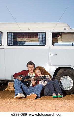 A young man playing his guitar for a young woman View Large Photo Image Stock Photo - A young man playing his guitar for a young woman. Fotosearch