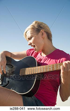 A young woman playing guitar View Large Photo Image Stock Image - A young woman playing guitar. Fotosearch