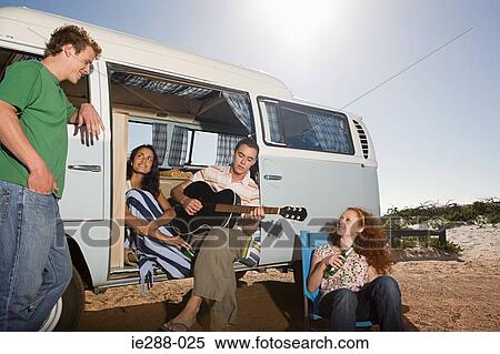 Stock Photography - Friends on the beach with a camper van. Fotosearch