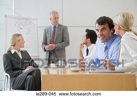 Stock Photography - Colleagues whispering in meeting. Fotosearch