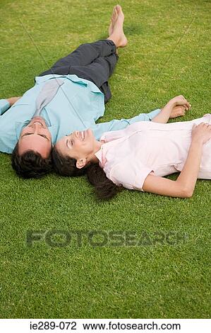Stock Image - Couple lying on grass. Fotosearch
