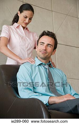 Stock Image - Woman giving massage to colleague. Fotosearch
