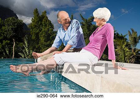 Picture - A couple sat next to a pool. Fotosearch