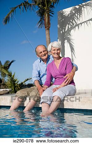 A couple sat next to a swimming pool View Large Photo Image Stock Photo - A couple sat next to a swimming pool. Fotosearch