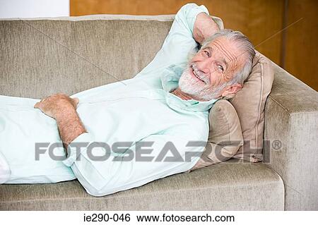 A senior man reclining on a sofa View Large Photo Image Stock Photograph - A senior man reclining on a sofa. Fotosearch