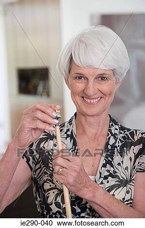 Stock Image - A senior woman holding a snooker cue. Fotosearch