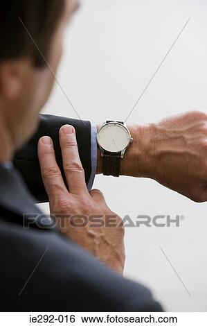 A businessman looking at his watch View Large Photo Image Stock Photograph - A businessman looking at his watch. Fotosearch