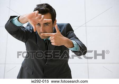 Stock Photography - Businessman looking through fingers. Fotosearch
