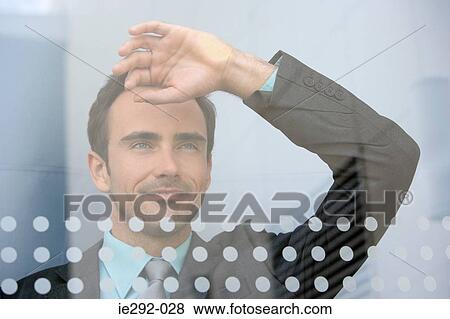 Stock Photo - Businessman looking through window. Fotosearch