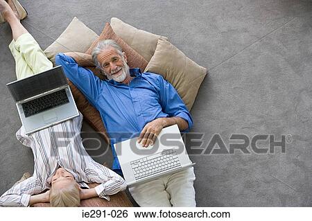 Couple relaxing with laptops View Large Photo Image Stock Photograph - Couple relaxing with laptops. Fotosearch