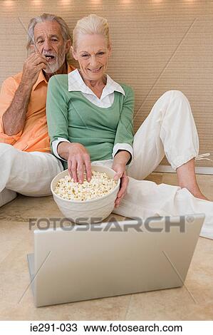 Stock Image - Couple watching movie on laptop. Fotosearch