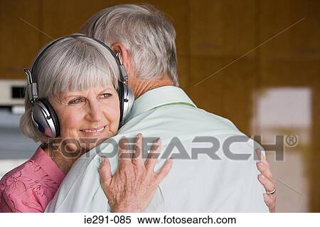 Stock Photography - Woman with headphones hugging husband. Fotosearch
