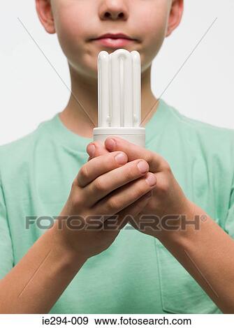Stock Photo - Boy holding an energy saving lightbulb. Fotosearch