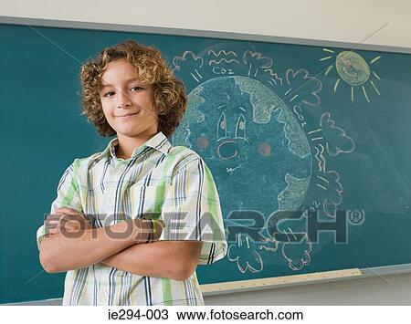 Boy standing by blackboard View Large Photo Image Stock Image - Boy standing by blackboard. Fotosearch