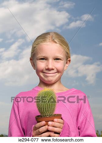 Smiling girl holding a cactus View Large Photo Image Stock Photo - Smiling girl holding a cactus. Fotosearch