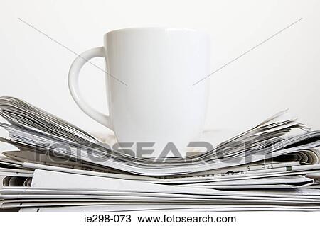 Stock Image - Cup on stack of newspapers. Fotosearch