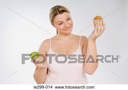 A woman deciding between a muffin and an apple View Large Photo Image Picture - A woman deciding between a muffin and an apple. Fotosearch
