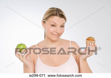 A woman deciding between a muffin and an apple View Large Photo Image Stock Image - A woman deciding between a muffin and an apple. Fotosearch