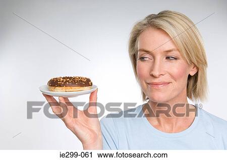 A woman holding a doughnut View Large Photo Image Stock Image - A woman holding a doughnut. Fotosearch