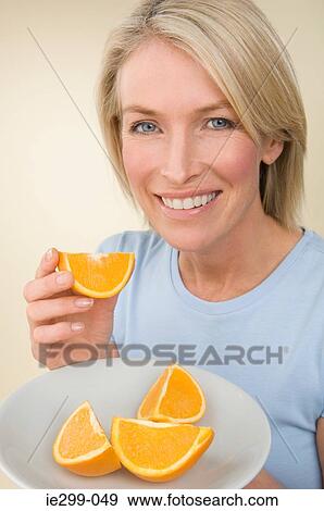 Stock Photo - A woman holding a plate of orange segments. Fotosearch