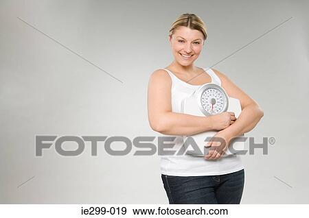 Stock Photo - A woman holding weight scales. Fotosearch