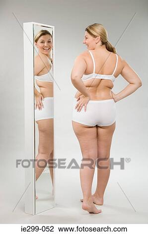 Stock Image - A woman looking in a mirror. Fotosearch