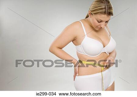 A woman measuring her waist View Large Photo Image Picture - A woman measuring her waist. Fotosearch