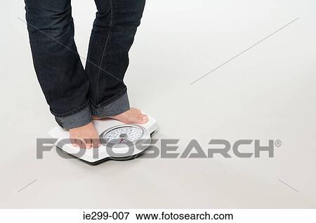 Stock Photo - A woman weighing herself. Fotosearch