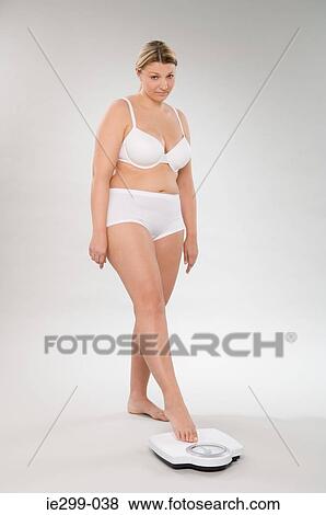 Stock Photo - An anxious woman weighing herself. Fotosearch