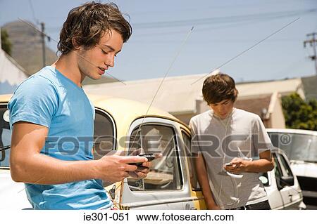Teenage boys listening to mp3 player and playing video game View Large Photo Image Stock Image - Teenage boys listening to mp3 player and playing video game. Fotosearch