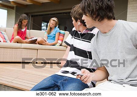 Stock Image - Teenage boys listening to music. Fotosearch