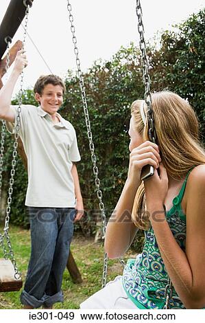 Stock Photo - Teenage girl and teenage boy sat on swings. Fotosearch