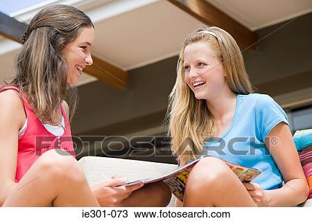 Stock Image - Teenage girls looking at magazines. Fotosearch