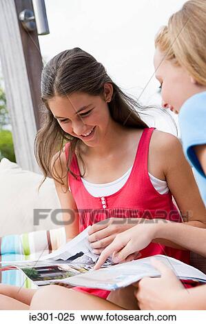 Teenage girls reading a magazine View Large Photo Image Stock Photography - Teenage girls reading a magazine. Fotosearch