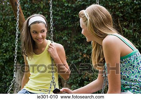 Teenage girls sat on swings View Large Photo Image Stock Image - Teenage girls sat on swings. Fotosearch