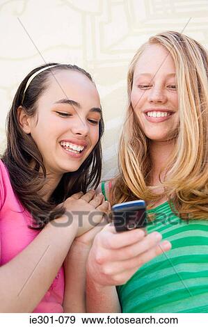 Teenage girls using a cell phone View Large Photo Image Stock Photo - Teenage girls using a cell phone. Fotosearch
