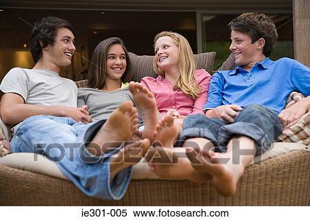 Stock Photography - Teenagers sat on a sofa talking. Fotosearch