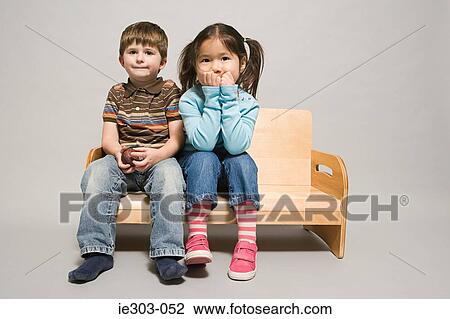 A boy and girl sat on a bench View Large Photo Image Stock Image - A boy and girl sat on a bench. Fotosearch