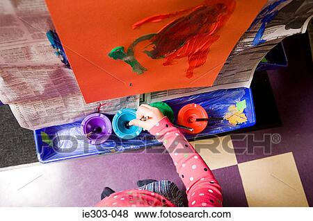 A girl putting a paintbrush in a paint pot View Large Photo Image Stock Photo - A girl putting a paintbrush in a paint pot. Fotosearch