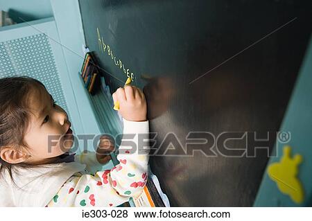 Girl writing on a blackboard View Large Photo Image Stock Photo - Girl writing on a blackboard. Fotosearch