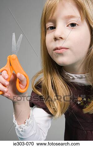 Stock Image - Girls holding a pair of scissors. Fotosearch