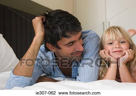 Father and daughter lying on a bed View Large Photo Image Stock Image - Father and daughter lying on a bed. Fotosearch