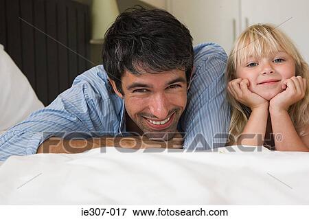 Father and daughter lying on a bed View Large Photo Image Stock Photo - Father and daughter lying on a bed. Fotosearch