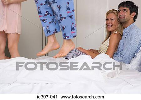 Parents watching their children jump on the bed View Large Photo Image Stock Image - Parents watching their children jump on the bed. Fotosearch
