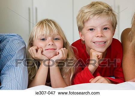 Portrait of children lying on a bed View Large Photo Image Stock Photo - Portrait of children lying on a bed. Fotosearch
