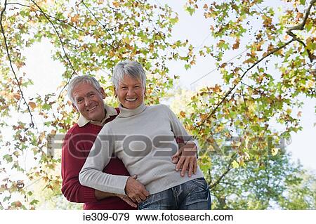 Senior couple hugging near trees View Large Photo Image Stock Photo - Senior couple hugging near trees. Fotosearch