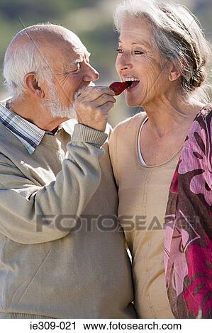 Stock Image - Senior couple sharing a strawberry. Fotosearch